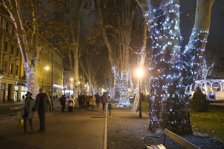 ZAGREB, CROATIA - DECEMBER 13th, 2017: Advent time in city center of Zagreb, Croatia. People passing through the Zrinjevac park ornate with illuminating trees.のeditorial素材