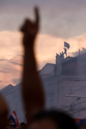 ZAGREB,CROATIA - JULY 16,2018 : Croatia National Team welcome home celebration for 2nd place on Fifa World Cup. Croatian football fans on top of the building with flag at sunset on Ban Jelacic square.のeditorial素材
