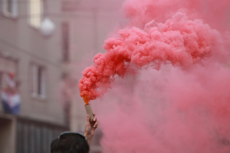 A man holding a hand flare with red smoke.の写真素材