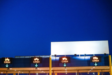 Empty white panel on the highway toll booth with cash signs at sunset.