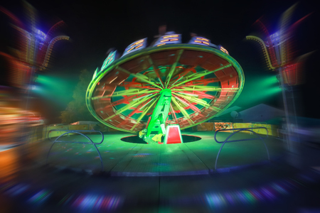 An illuminated rotating circular device in an amusement park with zoom in effect.の写真素材