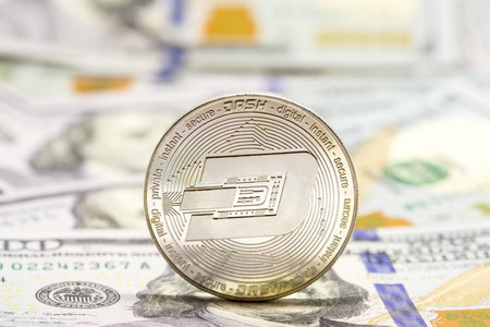 Cryptocurrency dash coin displayed on a heap of one hundred dollar bills.の写真素材