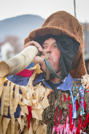Matulji, Croatia - 3rd February, 2019 : Man blows into horn during traditional carnival parade dressed up all colorful passing thru the street of Matulji.のeditorial素材