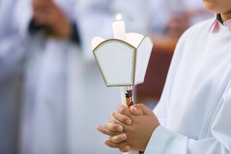 Children on the first holy communion in the church. Detail of the children holding the lighted holy...