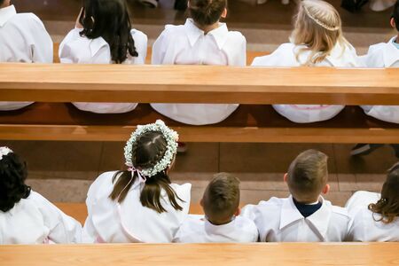 Children on the first holy communion in the church. View from above of children sitting in the bench during the first holy communion mass.の写真素材