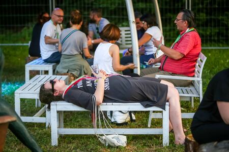 Zagreb, Croatia - 24th June, 2019 : Atmosphere during the 14th INmusic festival located on the lake Jarun in Zagreb, Croatia. Woman relax lying on the wooden bench during the festival.のeditorial素材