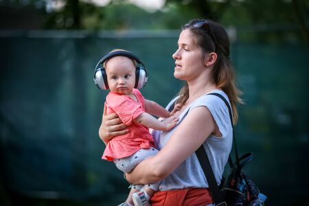 Zagreb, Croatia - 24th June, 2019 : Atmosphere during the 14th INmusic festival located on the lake Jarun in Zagreb, Croatia. Woman with baby that have headset to protect baby from loud sound.のeditorial素材