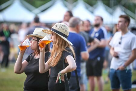 Zagreb, Croatia - 24th June, 2019 : Atmosphere during the 14th INmusic festival located on the lake Jarun in Zagreb, Croatia. Two girls drinking beer from plastic cups during festival.のeditorial素材