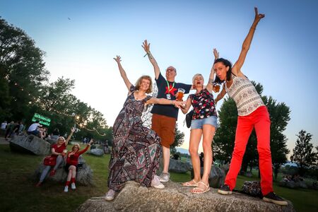 Zagreb, Croatia - 26th June, 2019 : Visitors of 3rd day of the 14th INmusic festival located on the lake Jarun in Zagreb, Croatia. Group of friends enjoy the festival by posing on the rock all happy.のeditorial素材