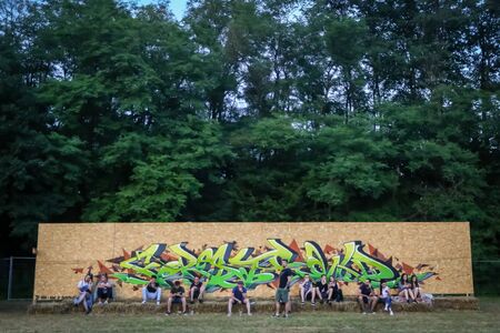 Brezje, Croatia - 20th July, 2019 : People resting on the stack of hay next to a wooden wall with graphite on the Forestland, ultimate forest electronic music festival located in Brezje, Croatia.のeditorial素材
