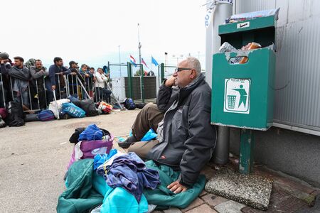 Bregana, Slovenia - September 20, 2015 : A senior Syrian refugee sitting on the ground next to a trash can on the slovenian border with Croatia. The migrants are waiting for the authorities to open the border crossing, so they can continue to the northernのeditorial素材