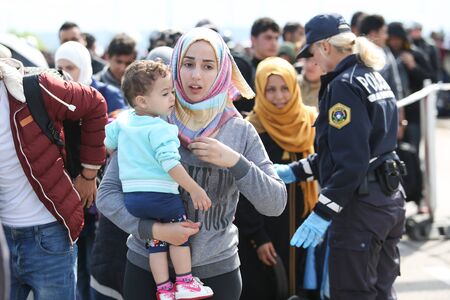 Bregana, Slovenia - September 20, 2015 : A young Syrian woman with a child in her arms walking towards the bus with the other refugees on the slovenian border with Croatia. The migrants are waiting for the authorities to open the border crossing, so they のeditorial素材