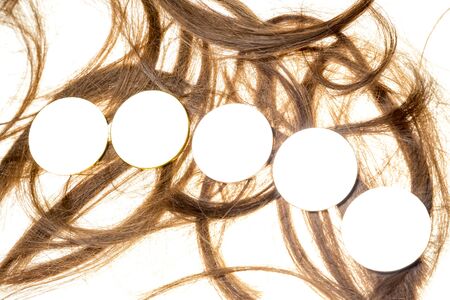 Lined up coins displayed on a heap of cut out woman hair, isolated on white background with.の写真素材
