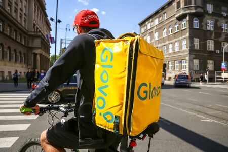 Zagreb, Croatia - October 20, 2019. Rear view of a worker with big yellow bag from Glovo, home delivery company for food and drink on the streets of Zagreb.のeditorial素材