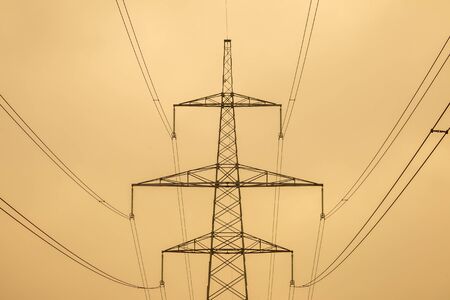 Silhouette of electric transmission tower, high voltage pole at cloudy day.