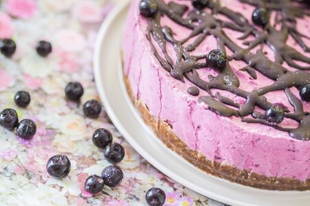 Pink raw vegan cake with cashew nuts and forest fruit topped with raw vegan chocolate with berries...