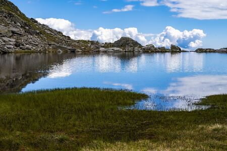 MOUNTAINS AND CLOUDS REFLECTED ON LAKE SAW DURING TREKKING
