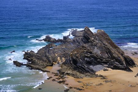 Waves crash on the cliff. Solo Backpacker Trekking on the Rota Vicentina and Fishermen's Trail in...