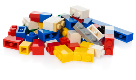 Stack of different colored blocks for children. Toy bricks in the colors: yellow, red, blue, gray, black on white background with slight reflection.の写真素材