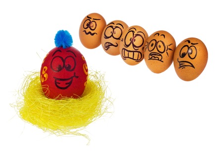 Easter eggs, hand-made painted in various patterns and colors with cartoon faces. Eggs in natural colors look with horror, astonishment and fear at colored smiling face of Easter eggs in a bird's nest.の写真素材