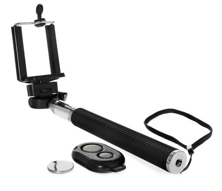 Selfie stick with remote control for taking pictures and videos. Silver monopod with black rubber handle. Hand holding smartphone on white background.の写真素材