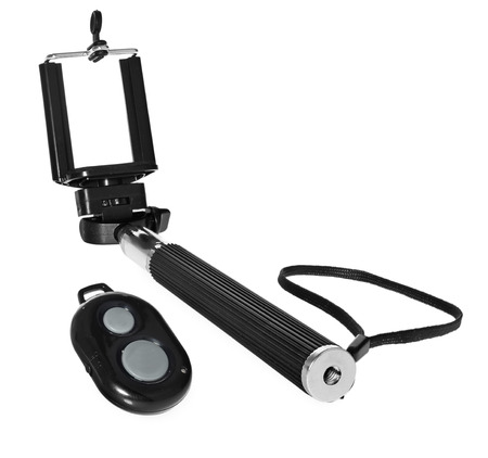 Selfie stick with remote control for taking pictures and videos. Silver monopod with black rubber handle. Hand holding smartphone on white background.の写真素材
