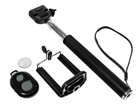 Selfie stick with remote control for taking pictures and videos. Silver monopod with black rubber handle. Hand holding smartphone on white background.の写真素材