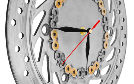 Handmade clock made of motorcycle parts. A clock face made of a brake disc decorated with hand-painted chain parts. Artistic object on a white background.の写真素材