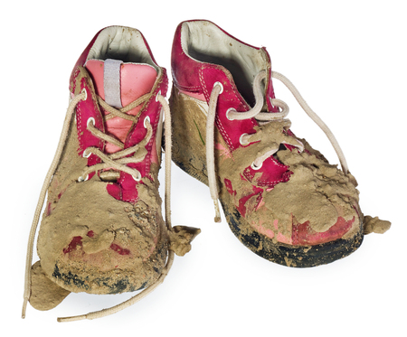 Children's tiny shoes covered with mud. Dirty leggings for children's feet in raspberry and white color isolated on a white background.の写真素材
