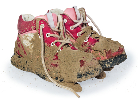 Children's tiny shoes covered with mud. Dirty leggings for children's feet in raspberry and white color isolated on a white background.の写真素材