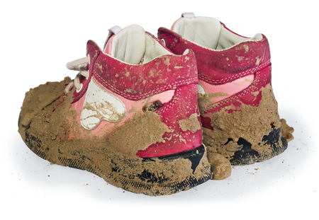 Children's tiny shoes covered with mud. Dirty leggings for children's feet in raspberry and white color isolated on a white background.の写真素材