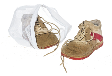 Wash bag for delicate clothes, shoes, underwear, bra. A laundry container made of white mesh filled with dirty children's shoes, isolated on a white background.の写真素材