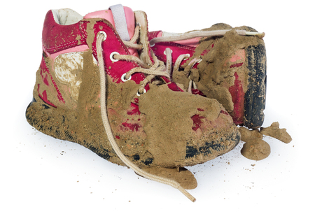 Children's tiny shoes covered with mud. Dirty leggings for children's feet in raspberry and white color isolated on a white background.の写真素材