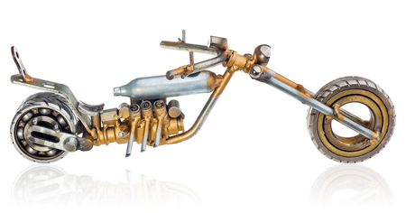 Handmade miniature of a chopper motorcycle. Decorative vehicle made of mechanical parts, bearings, wires, car candles, screws, plates. Toy in silver-gold colors, isolated on a white background.の写真素材
