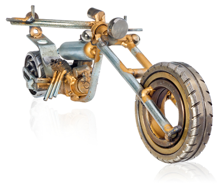 Handmade miniature of a chopper motorcycle. Decorative vehicle made of mechanical parts, bearings, wires, car candles, screws, plates. Toy in silver-gold colors, isolated on a white background.の写真素材