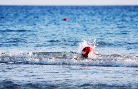 red sea buoy covered by a splashing waveの写真素材