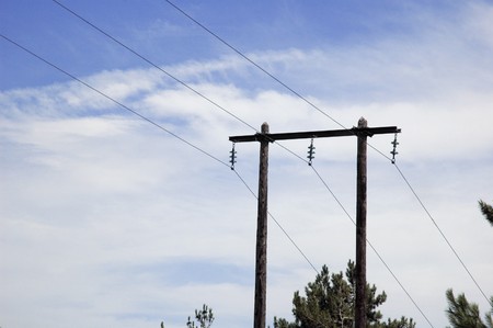 silhouette of retro electricity pylon with a blue cloudy sky 