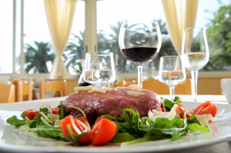 raw beef over a bed of rocket, flake of cheese and tomatoes の写真素材