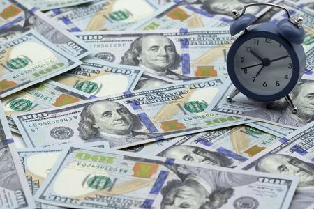 Time - money. Alarm clock on the stack of one hundred american dollars bills. Credit, deposit and...