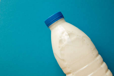 Fresh dairy product in full plastic bottle for milk, kefir or yoghurt with blue cap in center of...