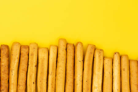 Italian grissini breadsticks. Tasty grissini snack on yellow background. Top view.