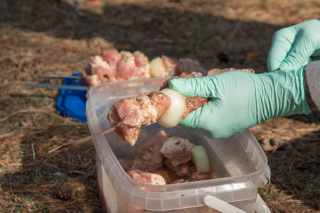 A man stringing marinated meat on a skewer for barbecue.の写真素材