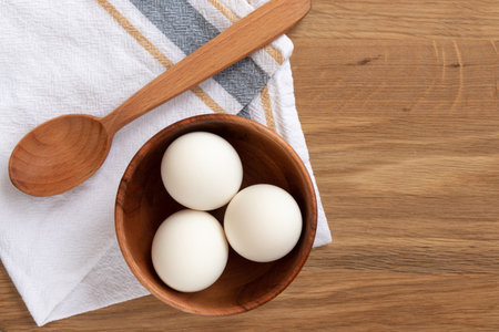 Baking ingredients - eggs inside a wooden plate and rolling pin over wooden background flat viewの写真素材
