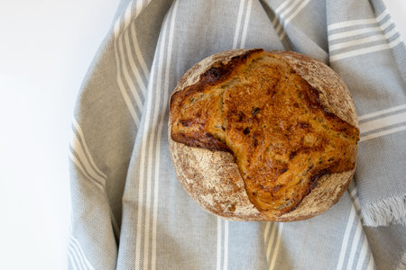 Homemade bread. Freshly baked round loaf of sourdough bread with linen cloth, front horizontal view.