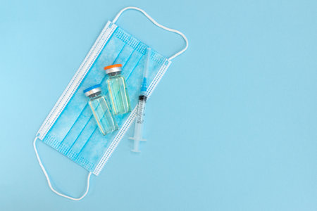 Vaccine vial, syringes and surgical mask isolated on white background, flat lay with space for text. vaccine concept. Vaccination and immunizationの写真素材