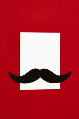 happy father day, composition of black mustache on envelope and empty space for text isolated on red background, greeting card with white sheet of paper and place for textの写真素材