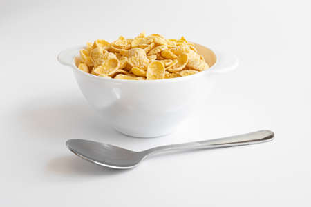 corn flake in bowl and spoon near isolated on white background, plate of cornflakes, healthy breakfast concept, side viewの写真素材