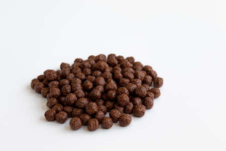 crunchy chocolate cereal balls isolated on white background, dry breakfast chocolate flavored balls