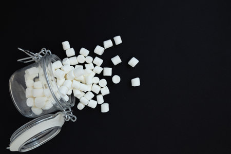 small white marshmallows in jar with space for text on on black, festive backgroundの写真素材