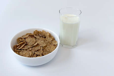 bowl of grain flakes and glass of milk isolated on white background, healthy breakfast with...